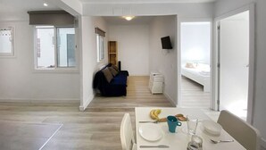 Amplia sala de estar con una mesa de comedor, un sofá y una cama al fondo.