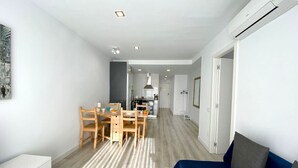 A modern apartment with a dining area, kitchen, and living space.