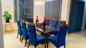 Un coin repas avec une table en verre, des chaises à revêtement bleu et des vases décoratifs.