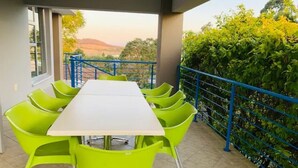 Un balcon avec une table et des chaises, une vue sur le paysage et une rambarde bleue.