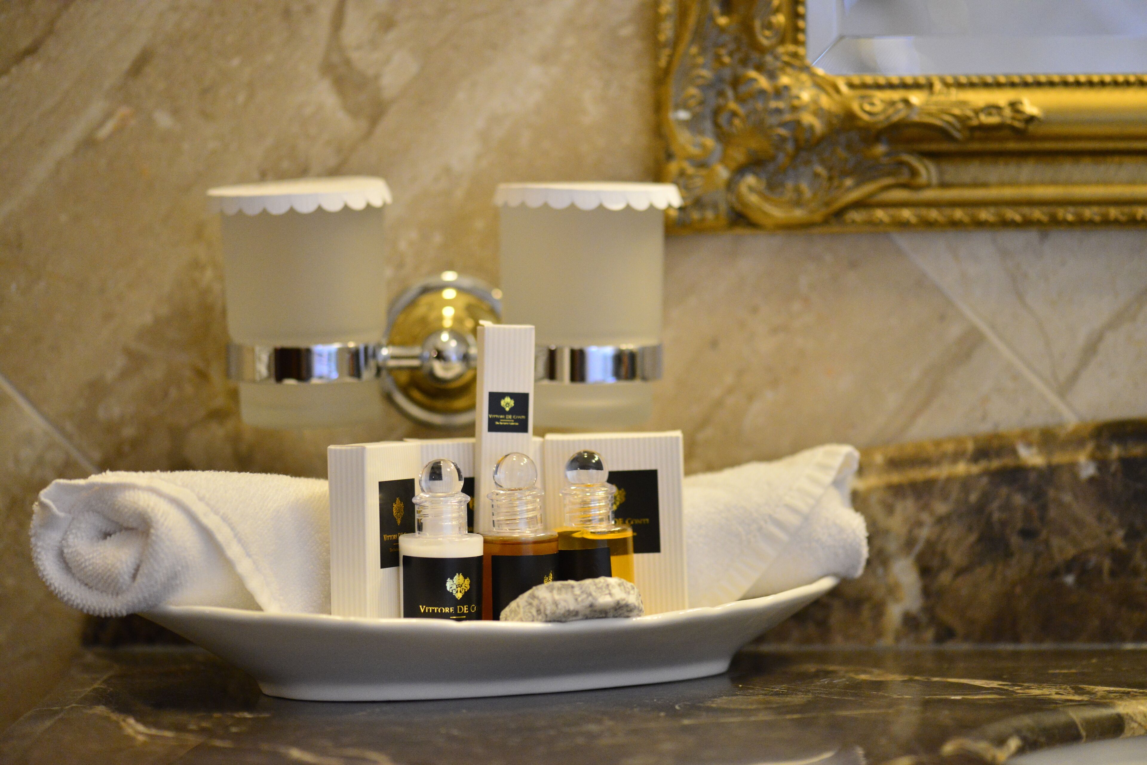 A bathroom with a marble countertop, a white towel, and two bottles of toiletries on a tray.