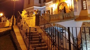 A historic building with a grand entrance, a staircase, and a well-lit facade. - Galicia Nueva castle hotel (Halic)