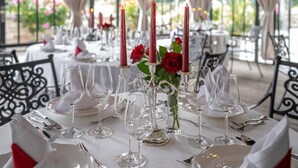 A table set for a formal dining experience with candles, clear glassware, and a vase with red roses. - Galicia Nueva castle hotel (Halic)