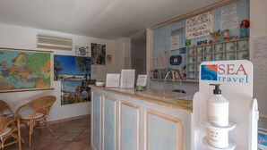 A reception area with a counter, a map, and a 'SEA travel' sign. - Holiday apartment with swimming pool and air conditioning (Budoni)