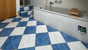 A bathroom with a checkered floor, a bathtub, and a shower area.