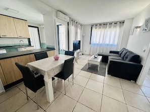 Un espacio habitable compacto con kitchenette, comedor y sofá.