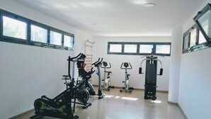 Une salle de sport équipée de machines de cardio, de poids libres et d’un mur recouvert de miroirs.