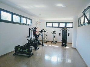 A gym with various exercise equipment, including treadmills and stationary bikes, and large windows providing natural light. - A1047 - Nice apartment in a complete urbanisation and close to the beach (Villajoyosa)