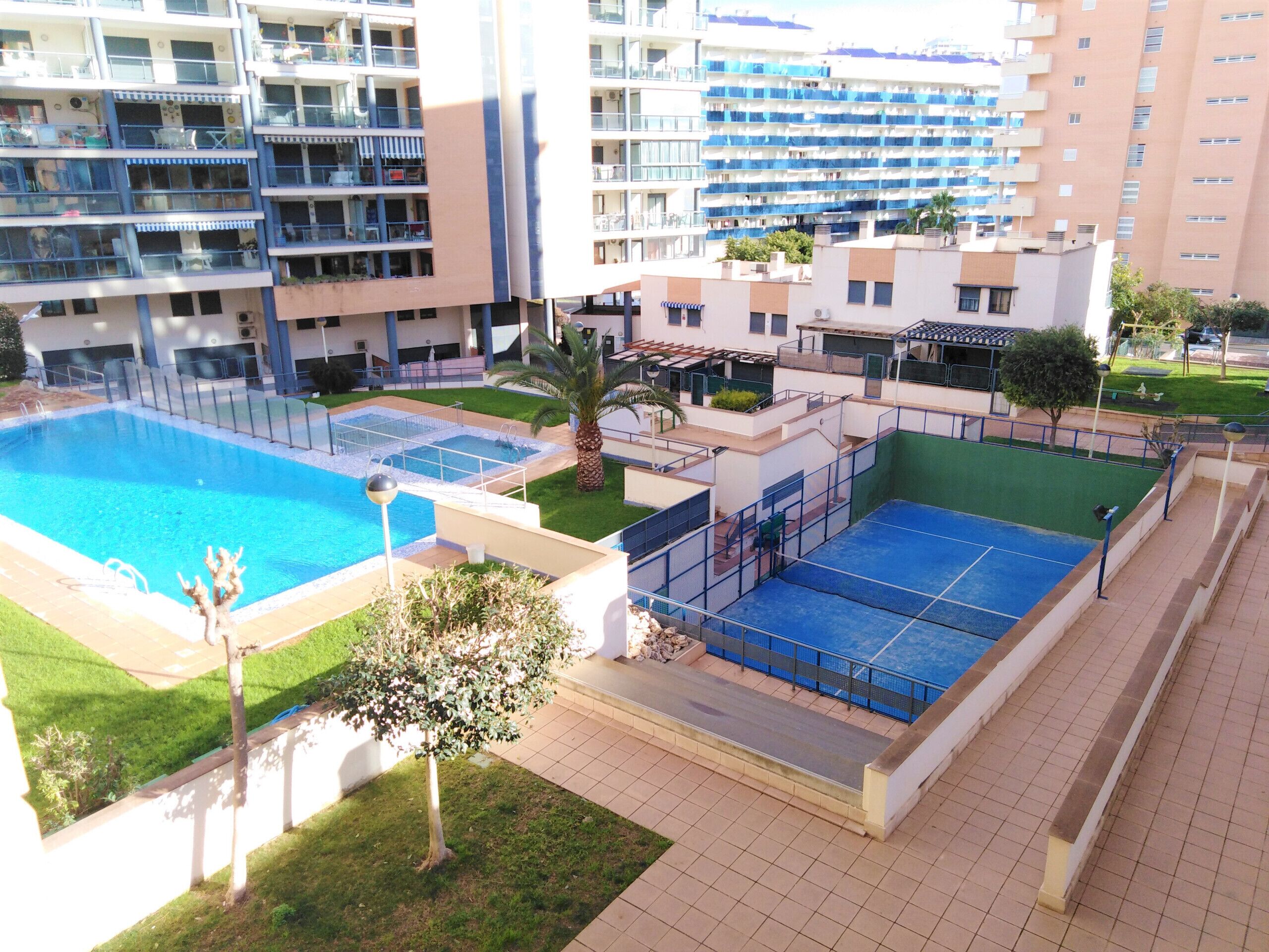 Un immeuble résidentiel doté d’une piscine, d’un court de tennis et d’un petit jardin.