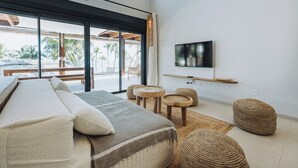 Une chambre moderne avec un grand lit, deux petites tables rondes en bois et un téléviseur fixé au mur.