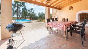 An outdoor patio with a pool, a barbecue grill, and a table with chairs.