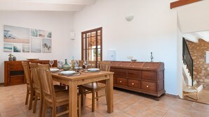 A dining area with a wooden table and chairs, a wooden cabinet, and a staircase leading to an upper level.