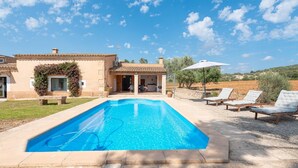 A swimming pool with lounge chairs and a covered patio area.