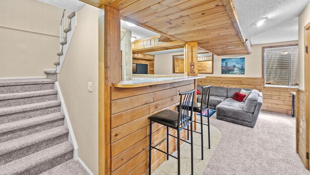 A wooden interior with a staircase, a bar area, and a gray sofa. - New! Recently Updated- Near Parks & Rec Center, Fenced Yard- 30 Day Rental (Littleton)