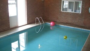 En inomhuspool med en vägg av tegelsten, ett fönster och en dörr.