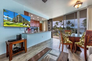 Ein modernes Wohnzimmer mit Fernseher, Holzmöbeln, einem Glastisch und einem Balkon mit Blick.