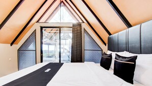 Un dormitorio con una cama grande, un cabecero y vistas a través de un ventanal.