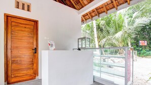 Un área de recepción con puerta de madera, un mostrador blanco y una mampara de vidrio.