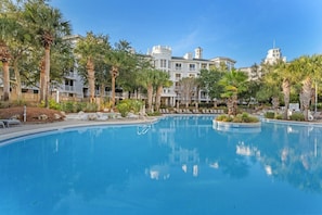 A swimming pool surrounded by palm trees and a hotel building with multiple balconies. - 🌊 Your Serene Sandestin Sanctuary 🌴 (Miramar Beach)
