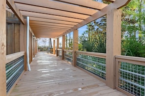 A wooden deck with a railing, a covered area, and a view of greenery. - 🌊 Your Serene Sandestin Sanctuary 🌴 (Miramar Beach)