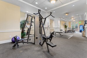 Ein Fitnessstudio mit verschiedenen Trainingsgeräten, darunter ein Kraftgerät, eine Trainingsbank und ein Ergometer.