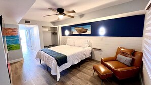 A bedroom with a bed, a brown leather chair, a ceiling fan, and a wall-mounted shelf. - Paradise Peak/New/Prime Location (Myrtle Beach)