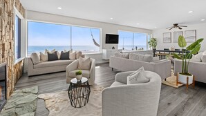 A spacious living room with large windows, a fireplace, and a view of the ocean. - Oceanfront Oasis Retreat (Dana Point)