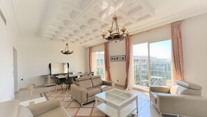 A spacious living room with a modern chandelier, a dining area, and a balcony with a city view. - FON3 (Cannes)