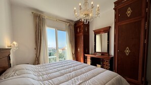 A bedroom with a large bed, a chandelier, a dresser, and a wardrobe. - FON3 (Cannes)