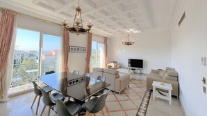 A spacious living area with a dining table, sofas, and a TV. - FON3 (Cannes)