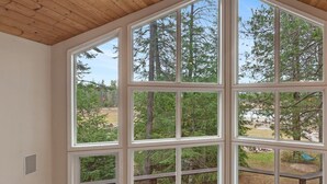 Ein Zimmer mit großen Fenstern, einer Holzbalkendecke und einem braunen Ledersofa.