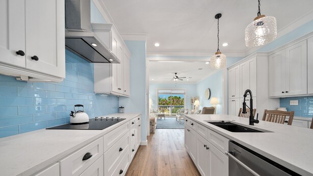 Una cocina moderna con armarios blancos, una estufa negra y una isla grande con un lavamanos.