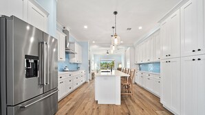 Una cocina moderna con electrodomésticos de acero inoxidable, armarios blancos y una isla central con asientos.