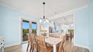 Un comedor amplio con una mesa y sillas de madera, un candelabro y vistas al exterior.