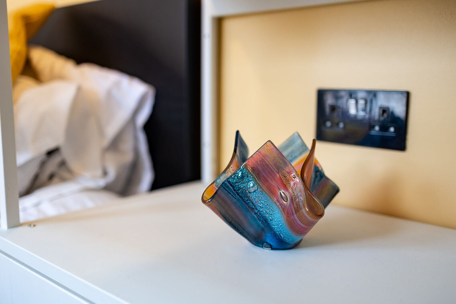 A room with a bed and a wall-mounted light switch.