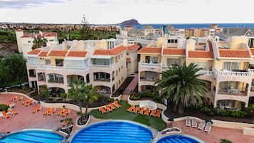 Un resort con varias piscinas, tumbonas y vistas al mar.