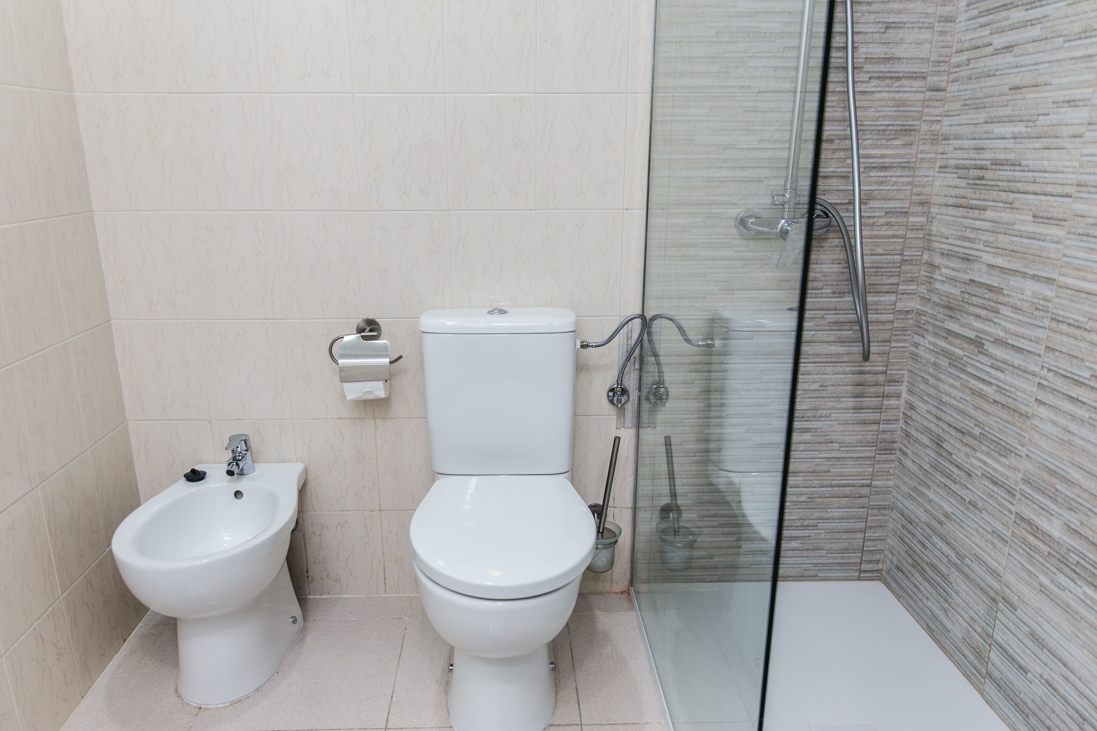 Un baño moderno con bidé, inodoro y cabina de ducha de vidrio.