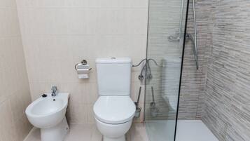 Un baño moderno con bidé, inodoro y cabina de ducha de vidrio.