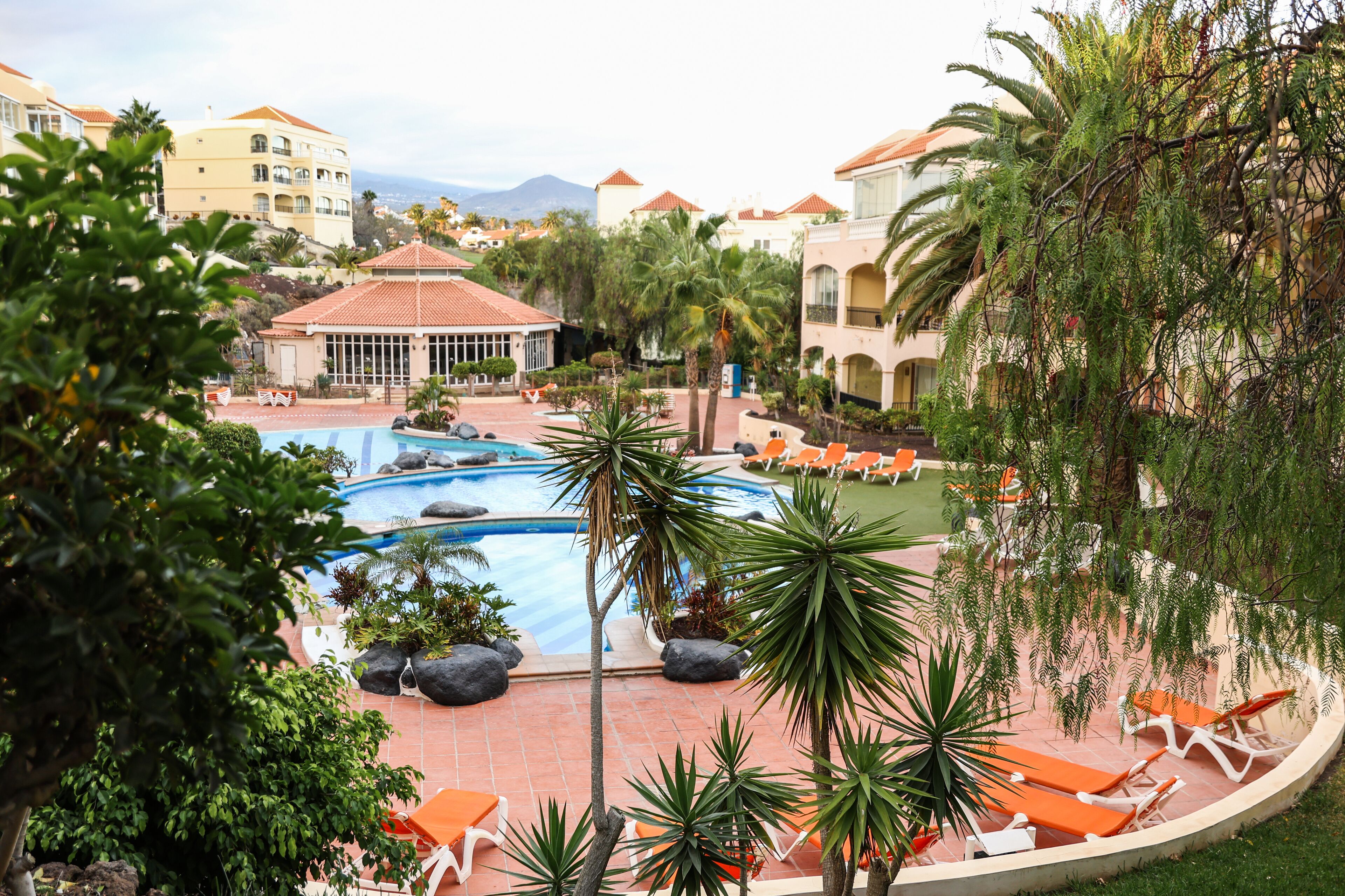 Ein Resort mit Swimmingpool, Liegestühlen und Palmen.