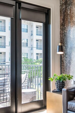 A modern room with a large window, a potted plant, and a lamp. - Comfortable Game-day condo near Vanderbilt with pool and game room (Nashville)