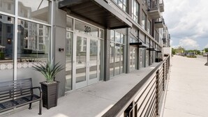 A modern building with a glass facade, numbered 303, and a bench with a potted plant on the sidewalk. - Comfortable Game-day condo near Vanderbilt with pool and game room (Nashville)