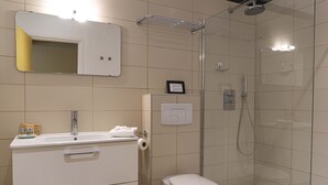 Un baño moderno con ducha, inodoro, lavamanos y espejo.