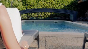 Zona de piscina con sillas de descanso y una plataforma curva con vistas.