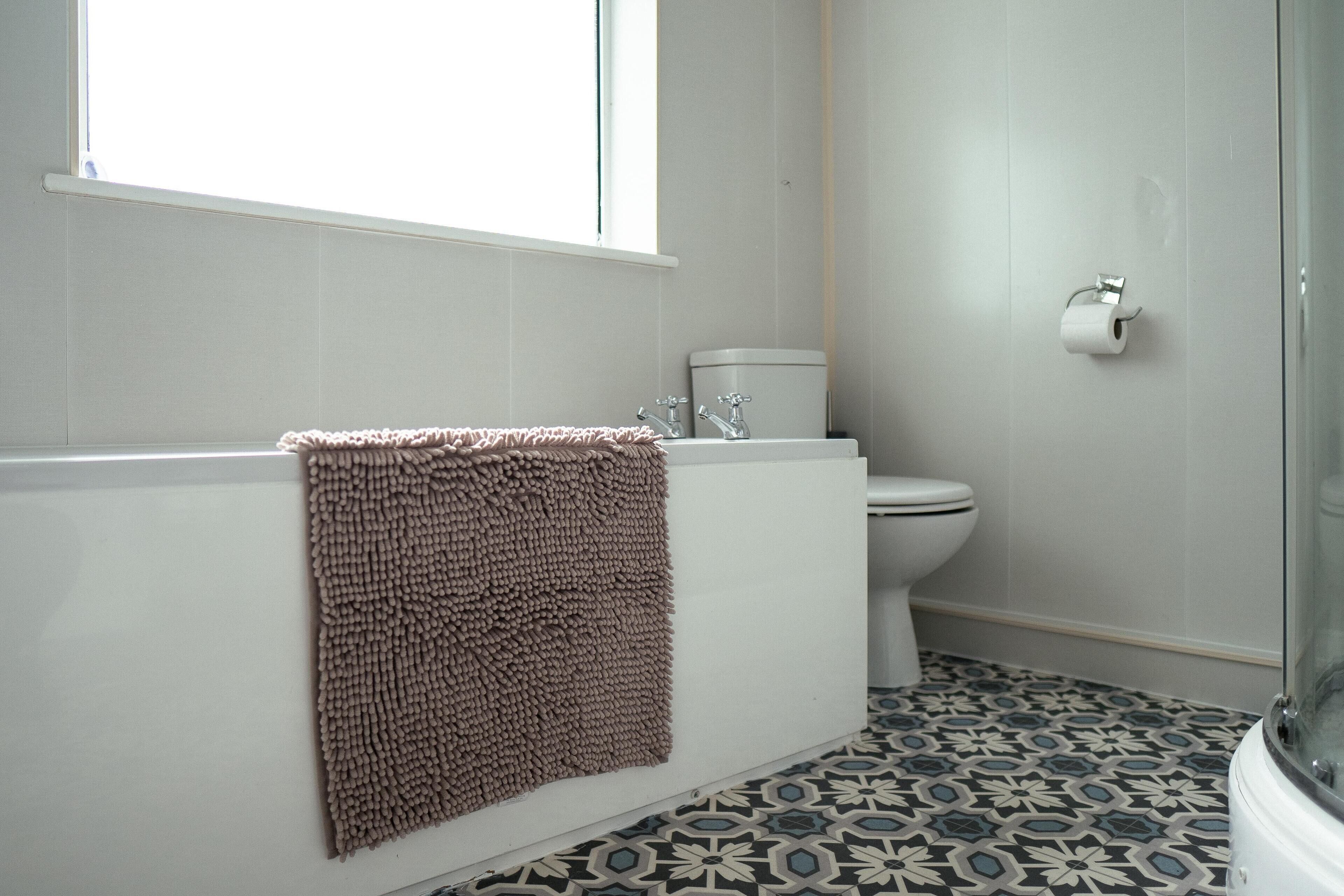 A bathroom with a white bathtub, a toilet, and a shower area.