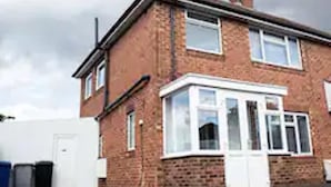 A two-story brick house with a white front door, a small porch, and a chimney. - Inviting 4-bed House in Kettering (Kettering)
