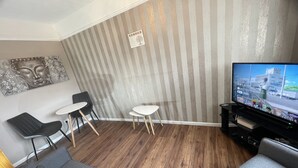 A living room with a TV, two chairs, a sofa, and a striped wall. - Comfy One Bedroom Apartment  (Darlaston)