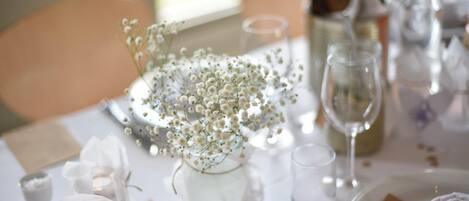 A table set with white tablecloth, clear glassware, and a centerpiece of white flowers.
