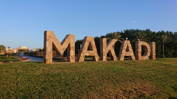 Large stone letters spelling "MAKADI" in a park setting with grass, trees, and a pathway. - Remarkable 2-bed Apartment in Makadi Heights (Makadi Bay)