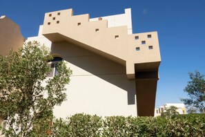 A modern building with a unique architectural design, featuring a prominent overhanging structure and multiple small windows. - Beautiful 2-bed Villa in Makadi Heights (Makadi Bay)