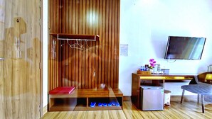 A hotel room with a wooden wardrobe, a desk with a computer, a television, and a shoe rack. - Thu Le Hotel (Cao Lanh)
